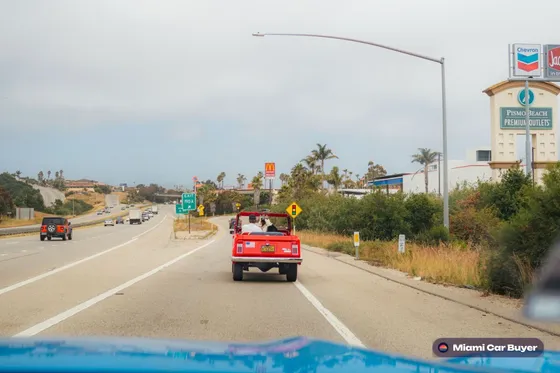 Red convertible cruising a coastal palm-lined road in Miami-Dade