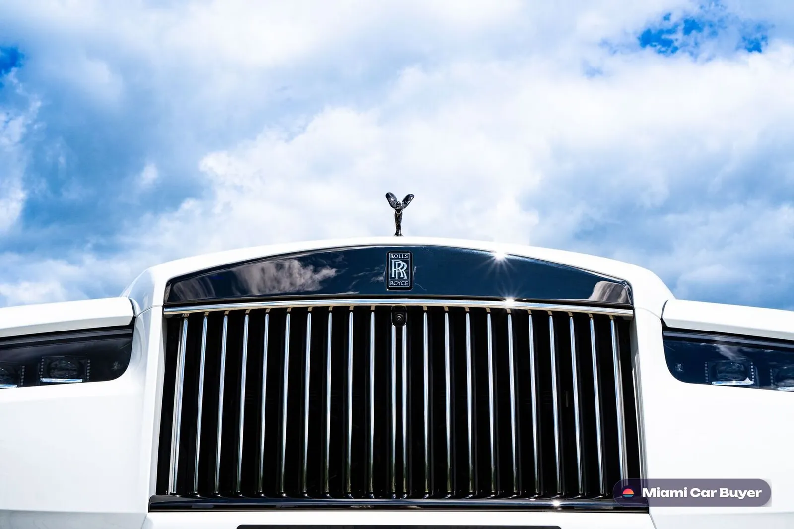 Rolls Royce grille and badge detail against blue sky, representing the premium guarantee of the locked offer