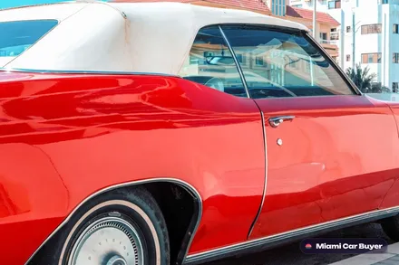Older red vintage convertible parked on a quiet Miami street, representing the cars sold here with or without a title