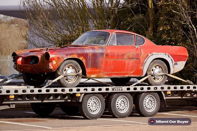 Flatbed tow truck loading a flood-damaged car in Miami-Dade for cash removal