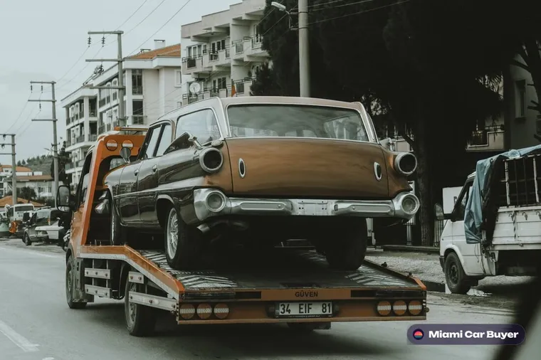 Flatbed tow truck loading a car for pickup on a Miami residential street