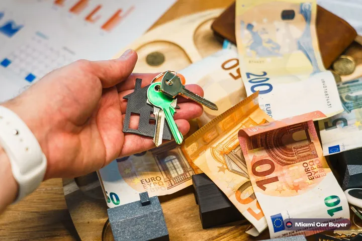 Hand holding cash and car keys at a Miami car sale, ready for same-day payment